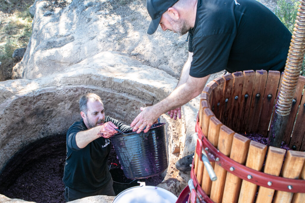 Viticultors de Ladiferenta buidant un cup de pedra medieval de 500 anys al Pla de Bages.