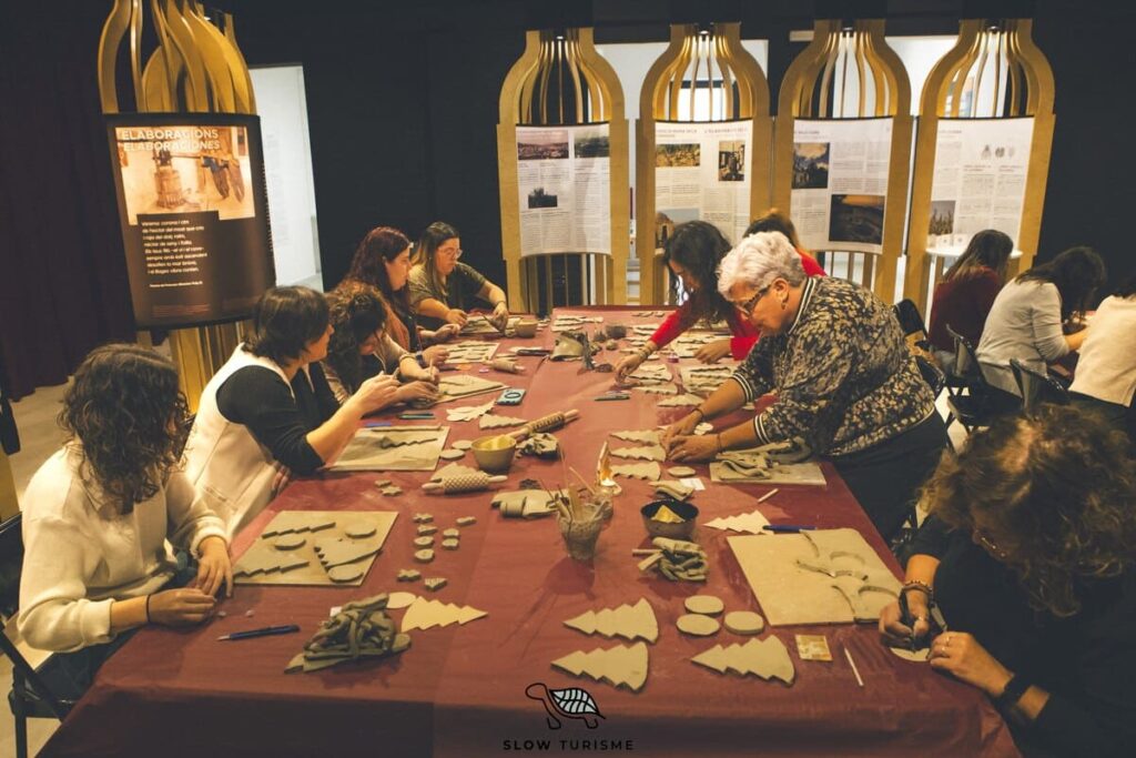 Participants creant peces de ceràmica durant el Taller de Ceràmica i Vermut de Nadal al Centre Enoturístic del Pla de Bages