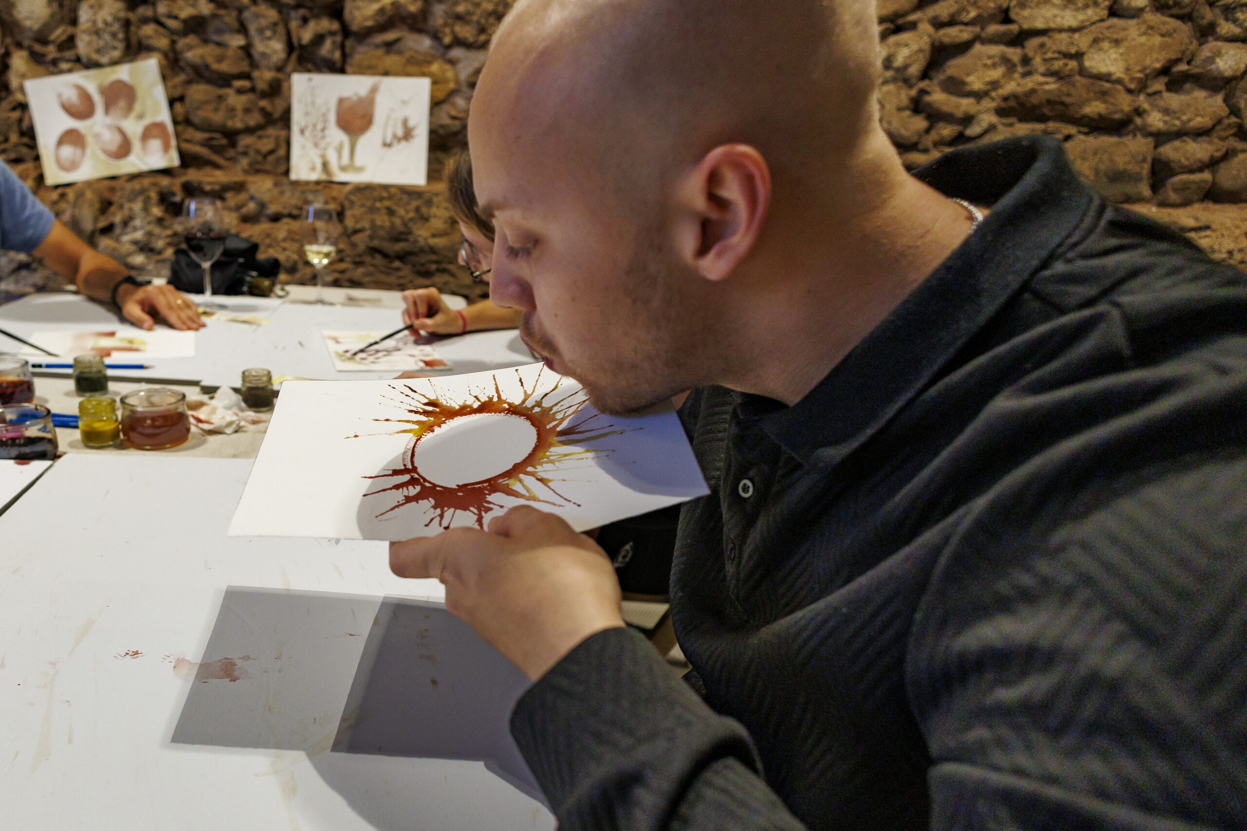Participant creant una pintura amb vi mitjançant la tècnica de bufat al ViArt d’Artés